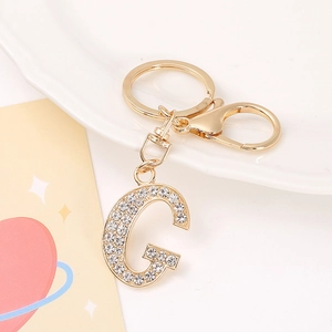 Detail shot of a gold-plated letter G keychain featuring high-quality white rhinestones