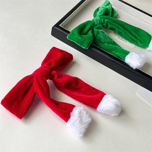 Detail view of red and green velvet Christmas hair clips with soft white plush pom-poms