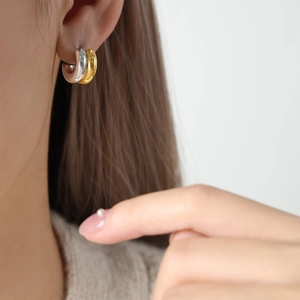 Close-up of double C-shaped gold and silver earrings on model featuring diamond accents