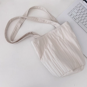Detalle del bolso tote plisado crema con textura de tela y correa larga para el hombro
