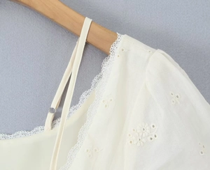 Close-up of floral embroidery and lace trim on a white puff sleeve mini dress