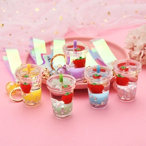 Five colorful liquid strawberry tea cup keychains with sequins on pink tray