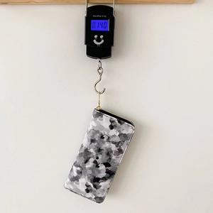 Long marble pattern women's wallet with gold zipper being weighed on a digital scale
