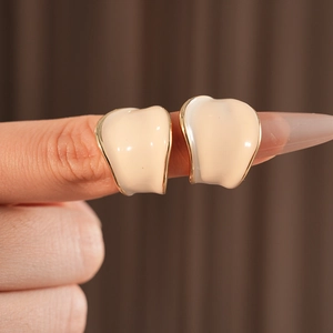 Dettaglio degli orecchini a forma di C in smalto beige con placcatura in oro a mano