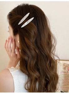 Détail de deux barrettes blanc nacré avec strass colorés portées par un mannequin