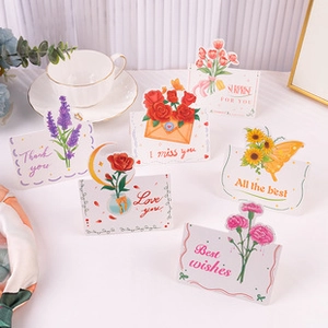Flat lay of colorful floral and butterfly shaped mini greeting cards with wishes
