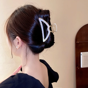 Gros plan d'une pince à cheveux nacrée effet sirène utilisée dans un chignon élégant