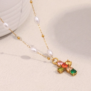 Détail du pendentif croix plaqué or 18K avec zircons colorés et des perles blanches