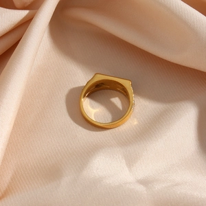 Macro shot of gold square ring on beige silk featuring side-set sparkling diamonds