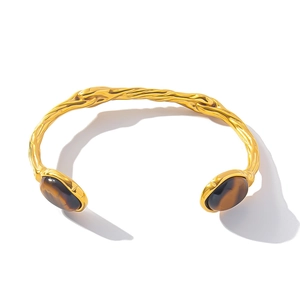 Close-up of golden vintage titanium steel cuff with two oval brown tiger eye stones
