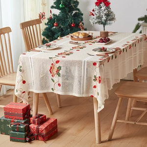 Detail view of festive Christmas embroidery with red bells and holly on cream lace tablecloth