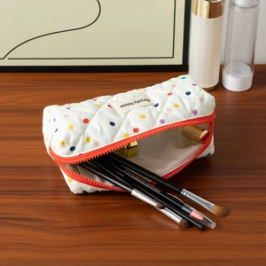 Close-up of quilted cotton pencil case with colorful polka dots and orange zipper detail