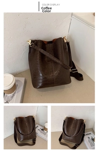 Detailed view of crocodile pattern dark brown bucket bag with wide textile strap