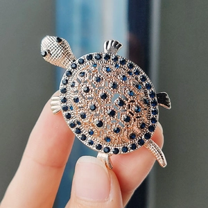 Charming turtle brooch in gold alloy with blue rhinestones and intricate hollow patterns