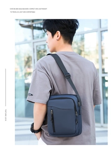 Borsa a tracolla da uomo blu navy in tessuto oxford indossata in un ambiente moderno