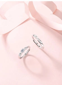 Close-up of S925 sterling silver couple rings with heart-shaped stone on pink silk ribbon