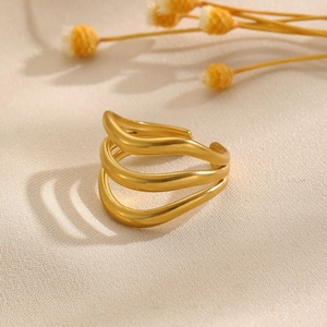 Gros plan d'une bague vague dorée multicouche avec finition mate sur tissu texturé