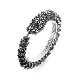 Vintage oxidized silver dragon bracelet with green gem eyes on a white background