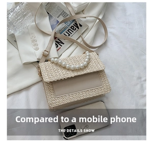 Detail of straw woven crossbody bag with pearl handle shown next to a smartphone for scale