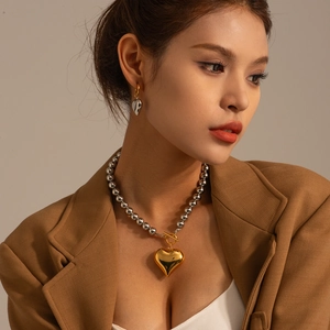 Detail of silver beaded necklace and earrings with large polished heart pendants on model