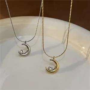 Detail of gold and silver crescent moon necklaces with crystals in a ceramic bowl