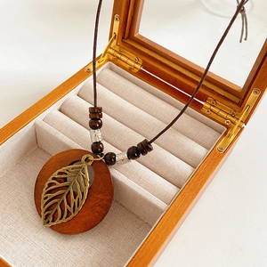 Détail du collier avec feuille évidée et perles de bois dans un coffret cadeau à bijoux