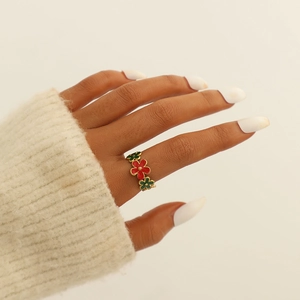 Detail of gold plated ring with green and red floral enamel patterns worn on finger