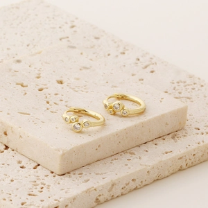 Close-up of gold S925 sterling silver hoop earrings with triple zircon stone clusters