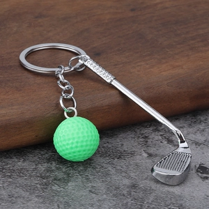 Close-up of golf club keychain with green ball on stone and wood background