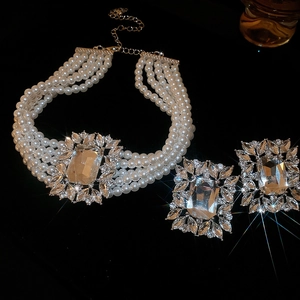 Macro shot of multilayer pearl necklace with leaf-shaped diamond and square crystal charms