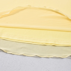 Dettaglio del tessuto a maglia giallo chiaro e trama a rete a strati sull'orlo