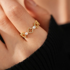 Détail macro d'une bague fleur plaquée or 18k avec trèfles, perles et zircons brillants