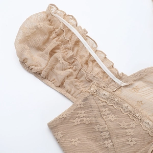 Detailed macro view of beige lace embroidery and delicate mesh ruffle on a summer camisole