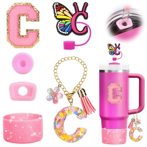 Close-up of pink glitter letter C resin charm and butterfly straw cover for Stanley cup