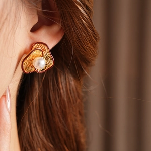 Close-up of vintage flower pearl earring with gold plating and red enamel detailing