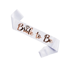 Close-up of white satin sash with rose gold Bride to Be lettering and diamond pattern
