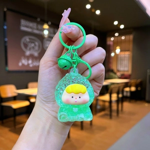 Gros plan d'un mignon porte-clés dessin animé vert avec effet sable et petit grelot