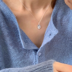 Macro di un medaglione religioso ovale in argento 925 su una catena a maglie fini