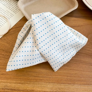 Detail view of polka dot fabric triangle hair clip on wooden table with elegant accessories
