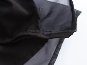 Dettaglio ravvicinato del tessuto in organza nera con cuciture in rete trasparente fine