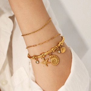 Close-up of 18K gold plated stainless steel bangle with starfish and conch charms