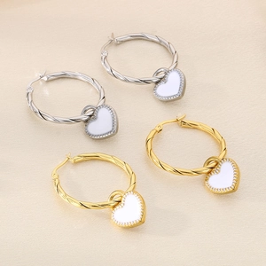 Close-up of heart-shaped enamel charms on gold and silver twisted hoop earrings