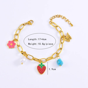 Detail view of gold chain bracelet with strawberry, flower, butterfly and pearl charms