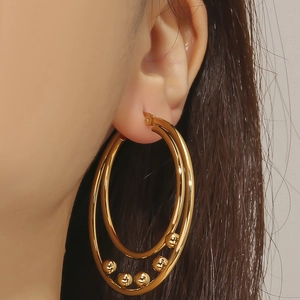 Women's gold titanium steel double hoop earrings with metal beads shown on model