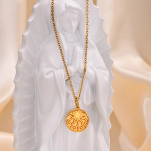 Close-up of golden sun and star embossed pendant necklace on a white statue background