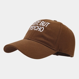 Detail view of brown cotton baseball cap featuring white CUTE BUT PSYCHO embroidery
