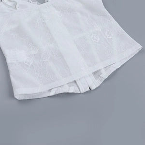 Close-up detail of white lace camisole showing intricate fabric texture and slim corset style