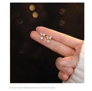 Detailed view of sterling silver bow earrings with sparkling cubic zirconia on finger