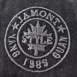 Macro shot of Jamont vintage crown embroidery detail on grey washed denim cap fabric