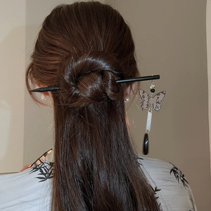 Close-up of hair bun styled with butterfly tassel hairpin and dangling black charms